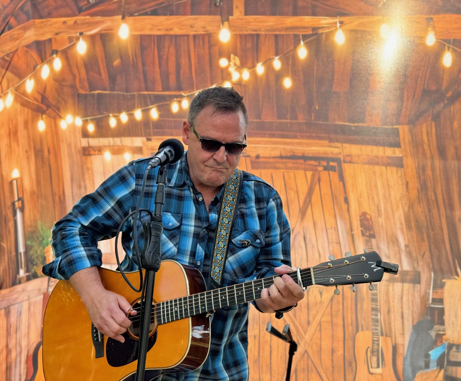 Jim Botsford playing acoustic guitar under string lights